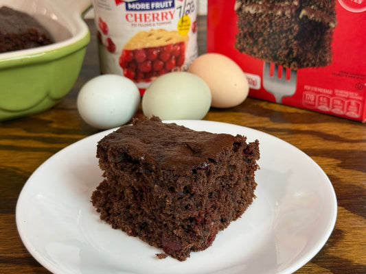 Slice of 3 ingredient chocolate cherry cake on a rustic farm kitchen table